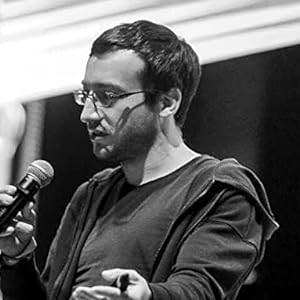Author speaking into a microphone wearing glasses and a hoodie