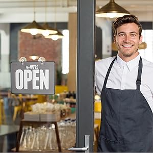 Photo of business owner with open sign to his storefront