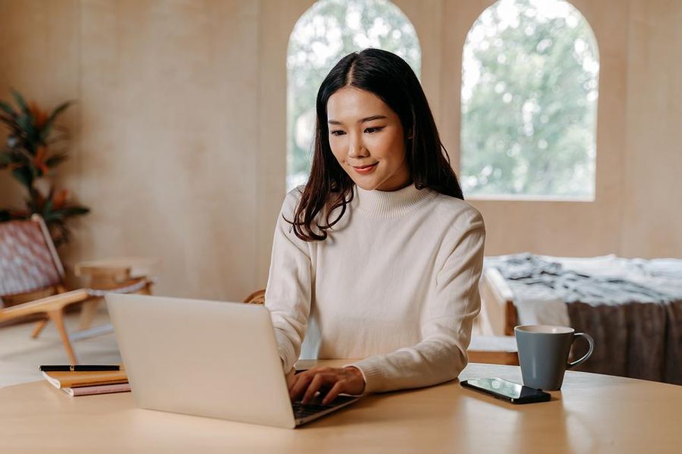 Woman on laptop adds bullet points to her resume