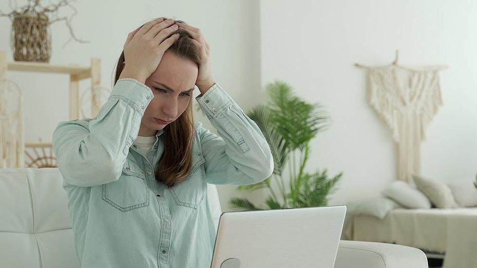 Woman on laptop miserable at work