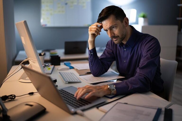 Man on laptop stressed about work