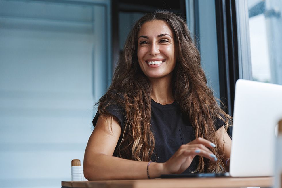 Businesswoman smiles while taking an online course on her laptop