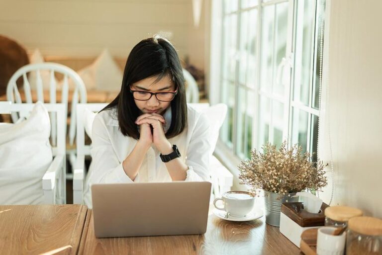 Woman on laptop thinks about filling out a job application after getting laid off