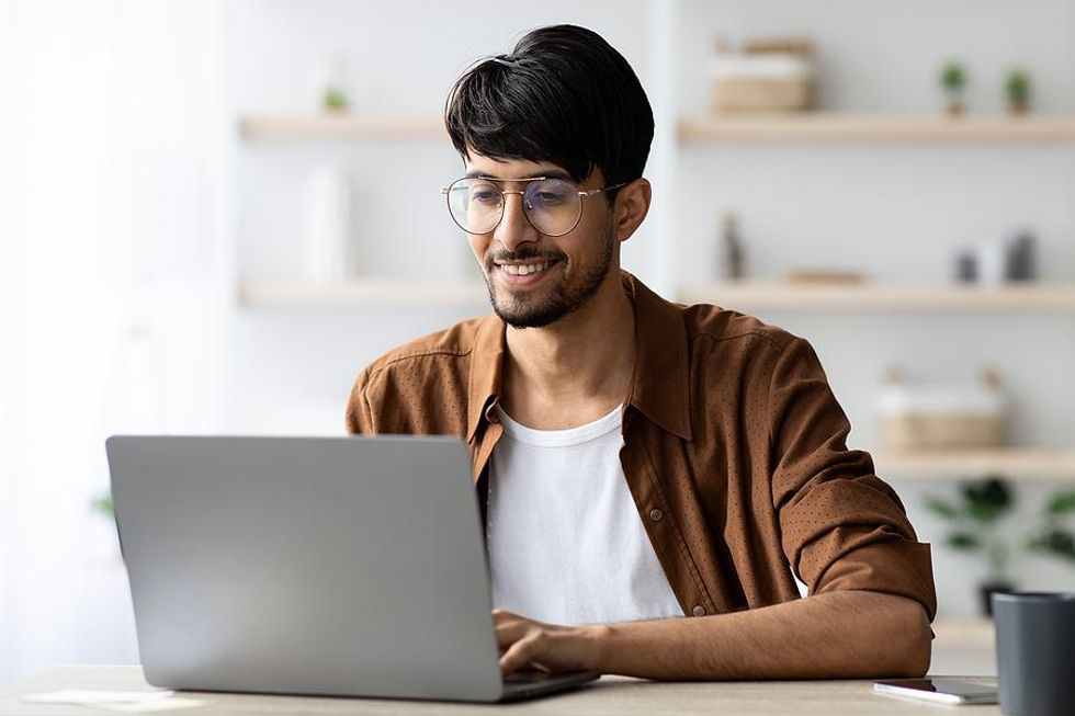 Man on laptop updates his LinkedIn profile and other social media accounts