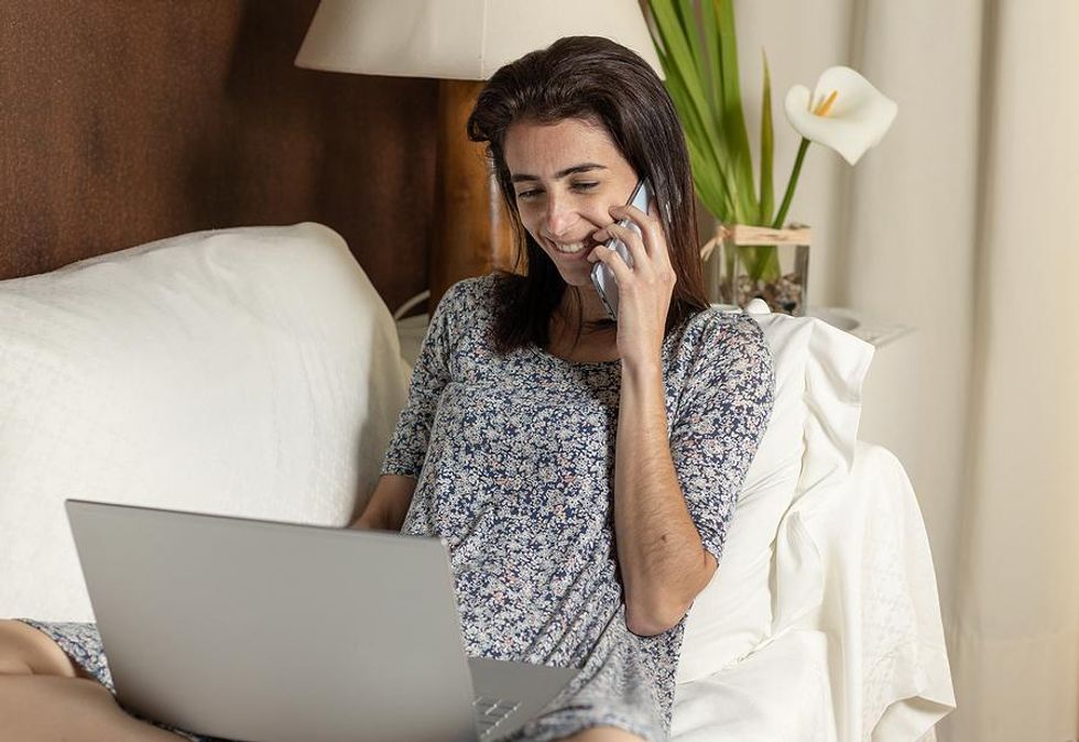 A woman speaks on the phone with a professional connection about a LinkedIn recommendation